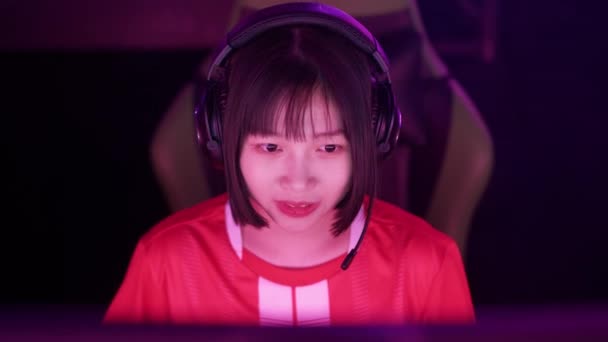 ハンドヘルド ヘッドフォンでアジアの女性ゲーマーの肖像画 ゲームでビデオゲーム サイバースポーツマン プレーヤー間のコミュニケーションを果たす — ストック動画