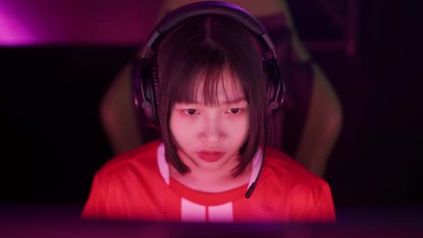 ヘッドフォンでアジアの女性ゲーマーの肖像画 ゲームでビデオゲーム サイバースポーツマン プレイヤー間のコミュニケーション チームとしてプレー — ストック動画