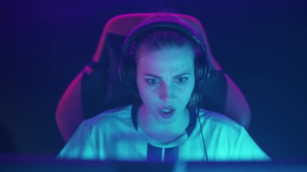 ヘッドフォンで感情的な女性ゲーマーの肖像画 ビデオゲーム 若いサイバースポーツマンが叫び 緊張した瞬間 勝利の感情をチームと伝える — ストック動画