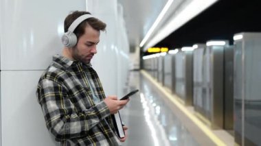 Genç adam metroda tren bekliyor, akıllı telefon kullanıyor ve kablosuz kulaklıkla müzik dinliyor, bir öğrenci üniversiteye okumaya gidiyor, toplu taşıma araçlarıyla..