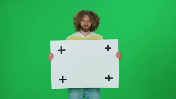 Junger Mann Steht Vor Grünem Hintergrund Und Hält Ein Weißes — Stockvideo