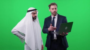 Takım elbiseli bir iş adamı dizüstü bilgisayar kullanır ve beyaz bir kanduradaki Arap iş ortağıyla iletişim kurar, projelere yapılan yatırımları tartışır, kroma anahtar şablonu.