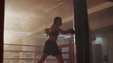 Kickboks, kadın boks, kadın boksör yumruklarını geliştirir, kum torbasını döver, boks salonunda antrenman günü, formda vücut, kız hızlı saldırır..