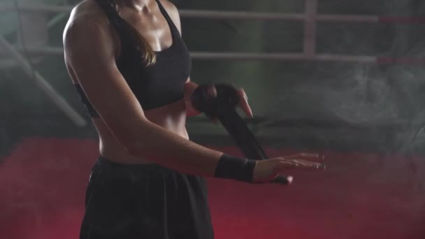 女性戦闘機は ボクシング包帯で彼女の手をラップ ジムでキックボクシングトレーニングの日 ネオン照明 — ストック動画
