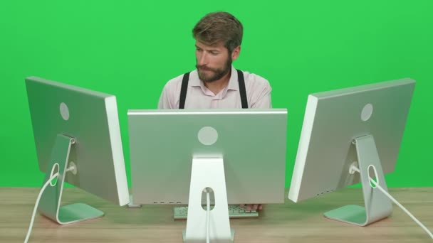 专注的开发人员在个人电脑上工作 坐在办公桌前 绿色背景 一个在监视器后面工作的人 色键模板 工作时的保安人员 前视镜 — 图库视频影像
