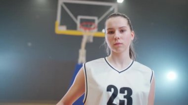 HANDHELD, genç bir bayan basketbolcunun portresi, elinde bir top tutuyor ve kameraya bakıyor, basketbol şampiyonası, ciddi görünüş, kadın gücü..