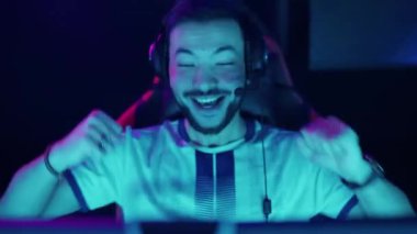 Neşeli bir oyuncunun portresi, bir video oyunu oynuyor, şampiyonada siber sporcu, takım oyunu kazandı, zafer duyguları, mavi neon ışığı.