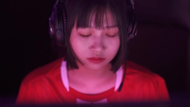 ハンドヘルド ヘッドフォンでアジアの女性ゲーマーの肖像画 ゲームでビデオゲーム サイバースポーツマン プレイヤー間のコミュニケーション 緊張した瞬間 — ストック動画