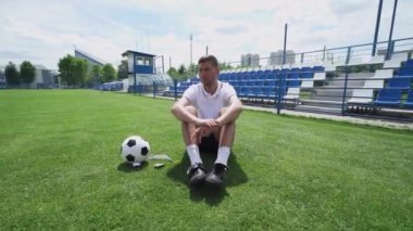 Genç erkekler futbol sahasında antrenman yapıyor, koç genç oyuncuları güneşli bir yaz gününde futbol konusunda eğitiyor ve eğitiyor..