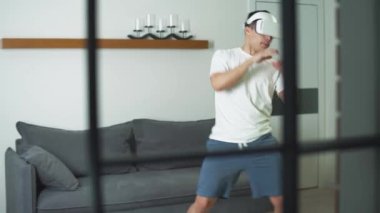 Fütüristik sanal gerçeklik gözlüklü adam dövüş oyunu simülatörü oynuyor. Modern teknolojiyi kullanarak kendini izole ediyor. Oturma odasında online spor eğitimi alıyor..