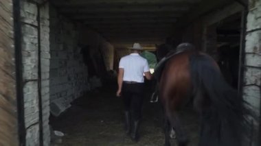 Çiftçi hayatı, şapkalı kovboy bir yürüyüşten sonra atı ahıra sokup çıkarıyor..