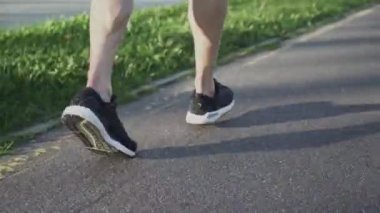 Koşucu şehir yolunda koşar, güneşli bir günde şehir ortamında antrenman yapar, yarışmalara hazırlanır, bacakların manzarası....