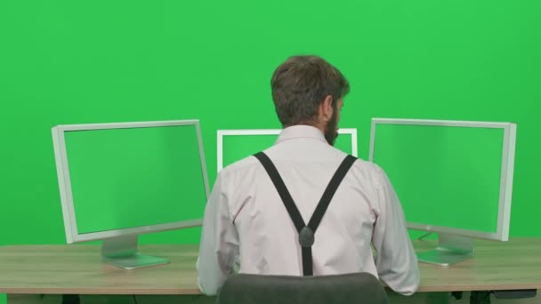 Softwareentwickler Arbeitet Während Schreibtisch Sitzt Grüner Hintergrund Wache Vor Monitoren — Stockvideo