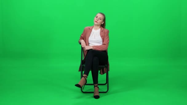 オフィスの椅子に座っているコートのかなり慎重な女性 緑の背景 エレガントな女性 待機プロセス — ストック動画