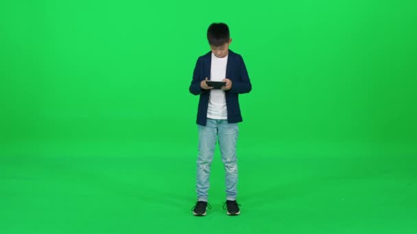 Zaostřený Asijský Školák Obleku Stojící Zeleném Pozadí Používající Tablet Obrazovce — Stock video