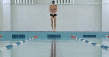 Genç atletik yüzücü suya atlıyor ve havuzda yüzüyor, adam suda antrenman yapıyor, 4 bin yavaş çekim..