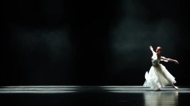 Bale, beyaz etekli zarif balerin siyah arka planda koreografik elementler sergilemek, güzel dramatik dans, 4k yavaş çekim..