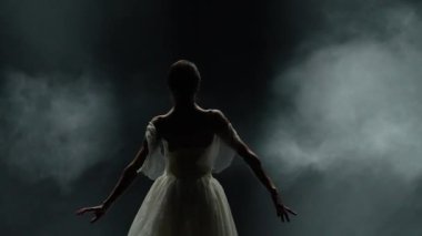 Bale gösterisi, beyaz etekli zarif bir balerin ve siyah arka planda dramatik koreografik elementler sergilemek, rüzgarlı ve güzel bir dans..