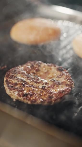 街头食品 在烤架上烹调汉堡包的过程 肉和面包在烤架上煎 汉堡包配料 垂直录像 4K超慢动作 — 图库视频影像