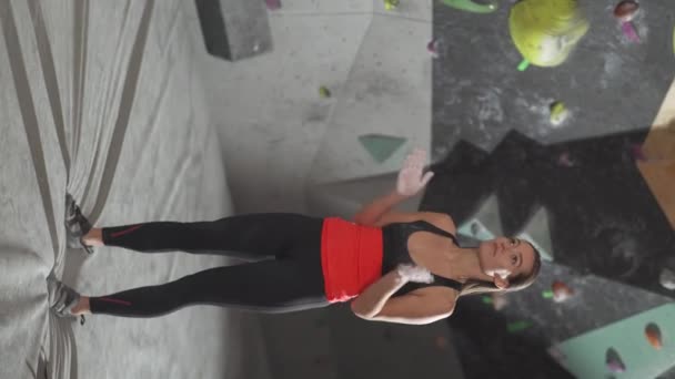 垂直ビデオ 女性のクライマーの肖像画は登山壁の背景に立ち 登る前にマグネシアを使用する — ストック動画