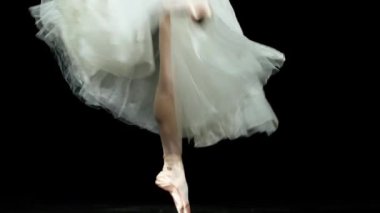 Rüzgarlı dans, beyaz elbiseli zarif balerin, dans balesi ve Pointe ayakkabılarıyla denge, bacakların görüntüsü, karanlık arka plan, dikkatli adımlar, 4k süper yavaş çekim.