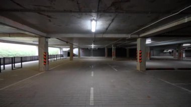 Boş yeraltı park alanı, beton duvarları, beton tüneli, kromakey şablonu olan bir ofis binasının otoparkında düzgün kamera hareketi..
