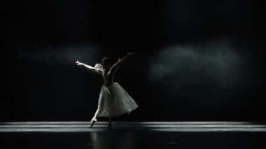 Bale performansı, beyaz etekli zarif balerin dansı ve siyah arka planda dramatik koreografik elementler sergilemek, rüzgarlı ve güzel bir dans..