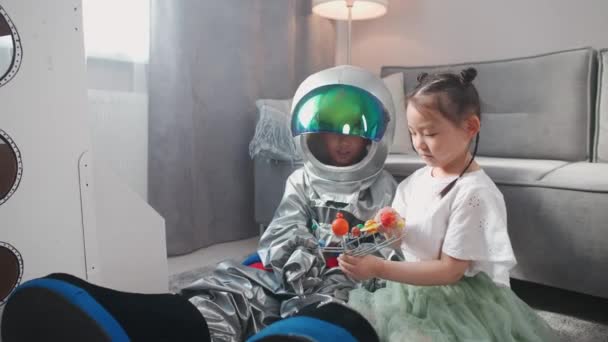 Kinesiska Barn Leker Vardagsrummet Hemma Pojke Astronautdräkt Sitter Golvet Med — Stockvideo