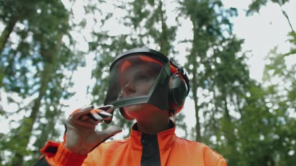 一名年轻的女伐木工人站在森林里 穿着防护服的女专家打开防护头盔的面罩 看着镜头 慢动作4K — 图库视频影像