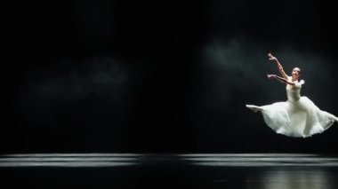 Performans, beyaz etekli zarif balerin ve siyah arka planda dramatik koreografik elementler sergilemek, rüzgarlı ve güzel dans, yavaş çekim..