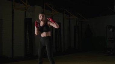 Genç kadın dövüşçü tekmelerini boks salonunda eğitiyor. Ön manzara, 4 km yavaş çekim..