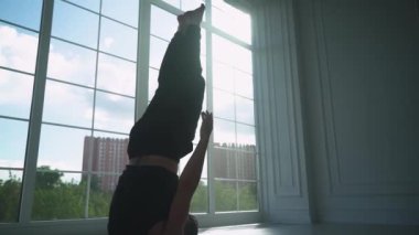 İyilik, ışıkla dolu beyaz bir odada yoga yapan genç bir adam, panoramik pencerenin yanında yoga yapan bir adam..