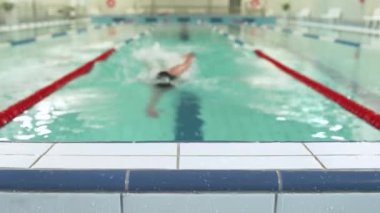 Genç bayan profesyonel yüzücü havuzda yüzüyor, spor takip cihazı kullanıyor, akıllı bir sepet kullanıyor, yüzme antrenmanını tamamlıyor, antrenman günü..