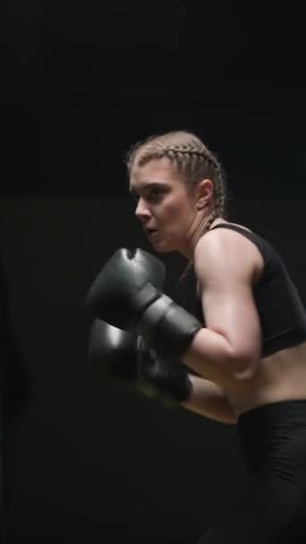 女性戦闘機はボクシングジムで彼のパンチと防衛を訓練し 少女は速く打つ パンチバッグを打つ 垂直ビデオ — ストック動画