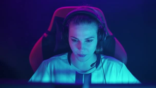 ヘッドフォンで感情的な女性ゲーマーの肖像画 ビデオゲーム 集中サイバースポーツマンは緊張した瞬間にチームとコミュニケーションをとります — ストック動画