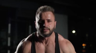 Halter, atletik adam halterle egzersiz yapıyor, halter kaldırıyor ve ağırlık çalışması yapıyor. Spor salonunda, portre, dramatik ışık, 4 km yavaş çekim..