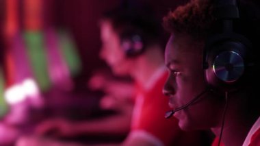 Odaklanmış oyuncular bir video oyunu oynuyor, siber sporcular yoğun oyun sırasında iletişim kuruyor, uluslararası şampiyonada takım oyunu, kırmızı neon ışığı.