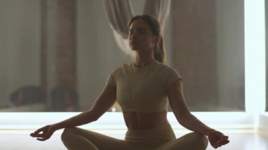 Sağlık, genç bir kadın yoga ve meditasyon yapıyor, sakin bir ruh hali, beyaz bir kadın yerde oturuyor..
