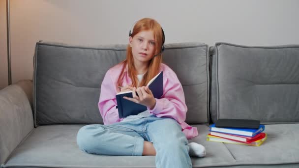 Fernstudium Rothaarige Teenagerin Sitzt Auf Der Couch Wohnzimmer Und Schreibt — Stockvideo