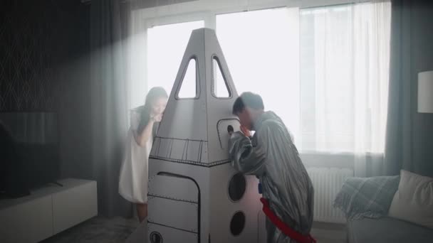 아들과 아시아 여자는 집에서 거실에서 그녀의 어머니와 우주선의 마분지 모델과 — 비디오