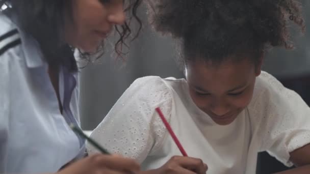 相当黑皮肤的女孩和她的妈妈坐在桌旁做作业 学习功课 在家学习 — 图库视频影像