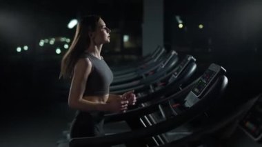 Sağlık, koşu bandında koşan genç bayan sporcu, spor salonunda aerobik egzersiz ve dayanıklılık eğitimi, gece hayatı..