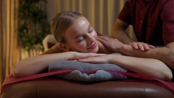专业按摩师为年轻女性提供轻松的背部按摩 漂亮的女性享受按摩 温暖的照明 温泉治疗 — 图库视频影像