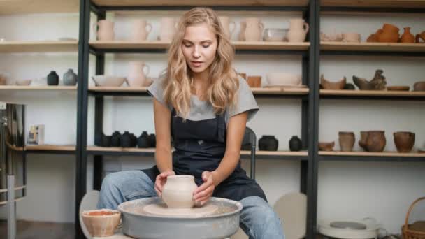 陶器の研修会 仕事でかわいい女性の陶芸家は粘土 手工芸 若い女性からピッチャーを作りますオンラインでマスタークラスを教えます — ストック動画