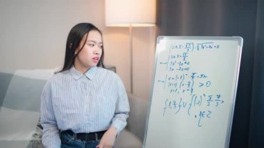 Asyalı kadın öğretmen çevrimiçi matematik dersi veriyor, öğrenme sürecinin canlı yayını, evde eğitim, video aracılığıyla evde eğitim.