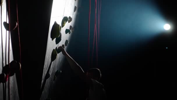 年轻的登山者在攀岩墙上接受训练 练习攀岩和爬山 使用保险和电影照明 — 图库视频影像