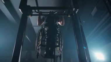 Belarus, Minsk - 24 Eylül 2021: Tekerlekli sandalyedeki engelli sporcu, yatay barfiks, beden eğitimi ve fiziksel aktivitede barfiks çekiyor..