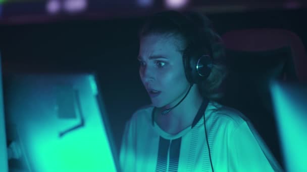 ヘッドフォンの感情的な女性ゲーマーの肖像画は ビデオゲームをプレイし チームと通信し チームはラウンドを失いました ブルーネオンライト — ストック動画