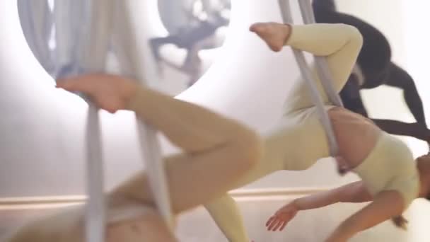 伸展舞 一组在镜室里做瑜伽的女运动队 年轻的女人们用瑜伽元素跳着舞 伸展在一个用布绳装饰的房间里 — 图库视频影像