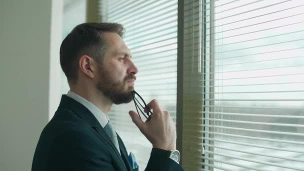 Сосредоточенный Бизнесмен Костюме Стоит Панорамного Окна Офисе Отражает Мыслительный Процесс — стоковое видео